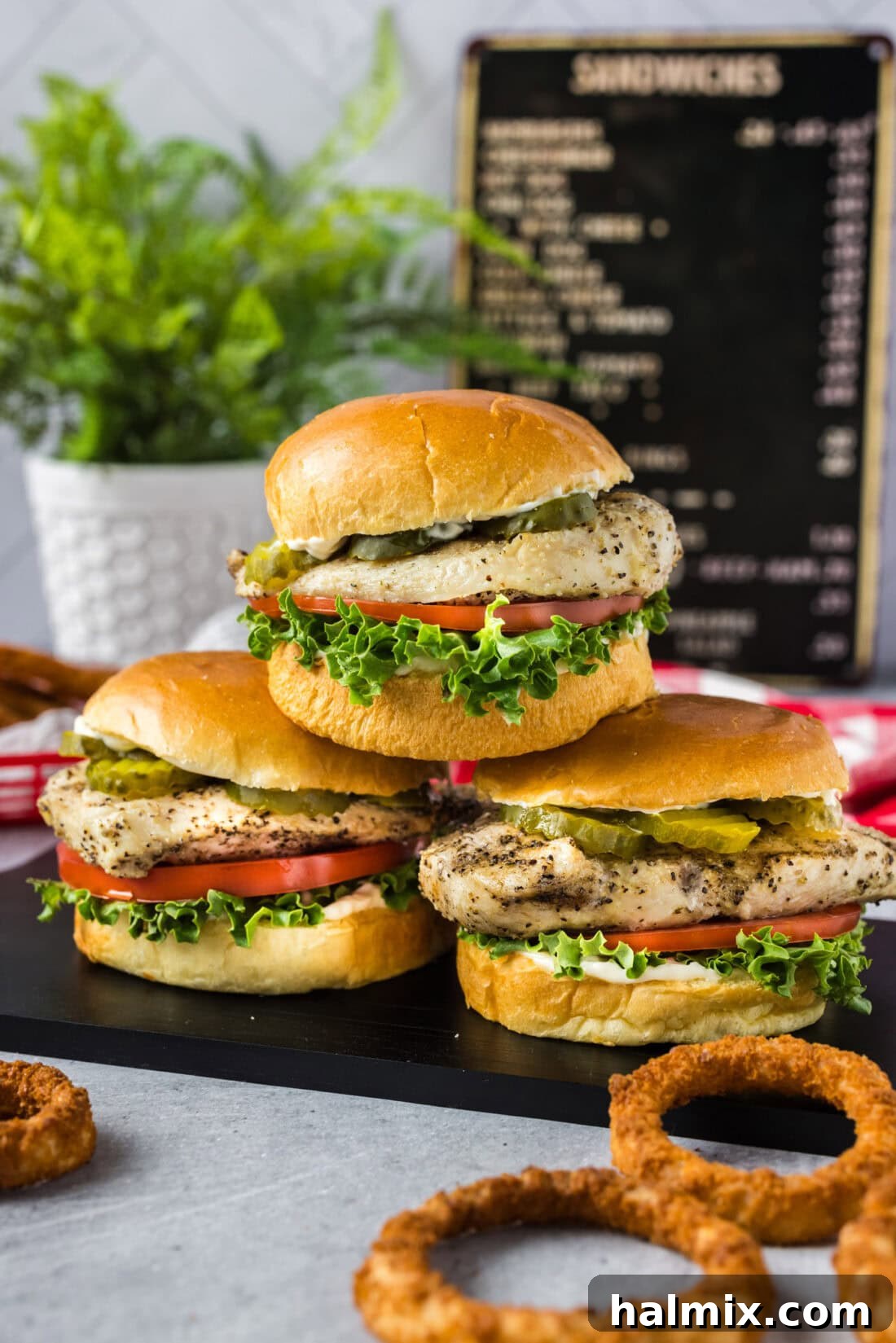 Three perfectly stacked grilled chicken sandwiches with fresh toppings