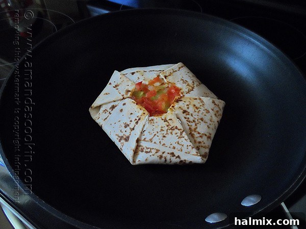 A homemade Crunchwrap Supreme, perfectly grilled to golden brown on one side, flipped over in a skillet to cook the other side to a similar crispy texture.