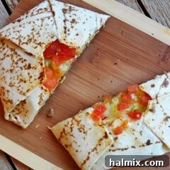 An overhead photo of a copycat crunchwrap supreme cut in half on a wooden cutting board, showcasing its delicious layers.