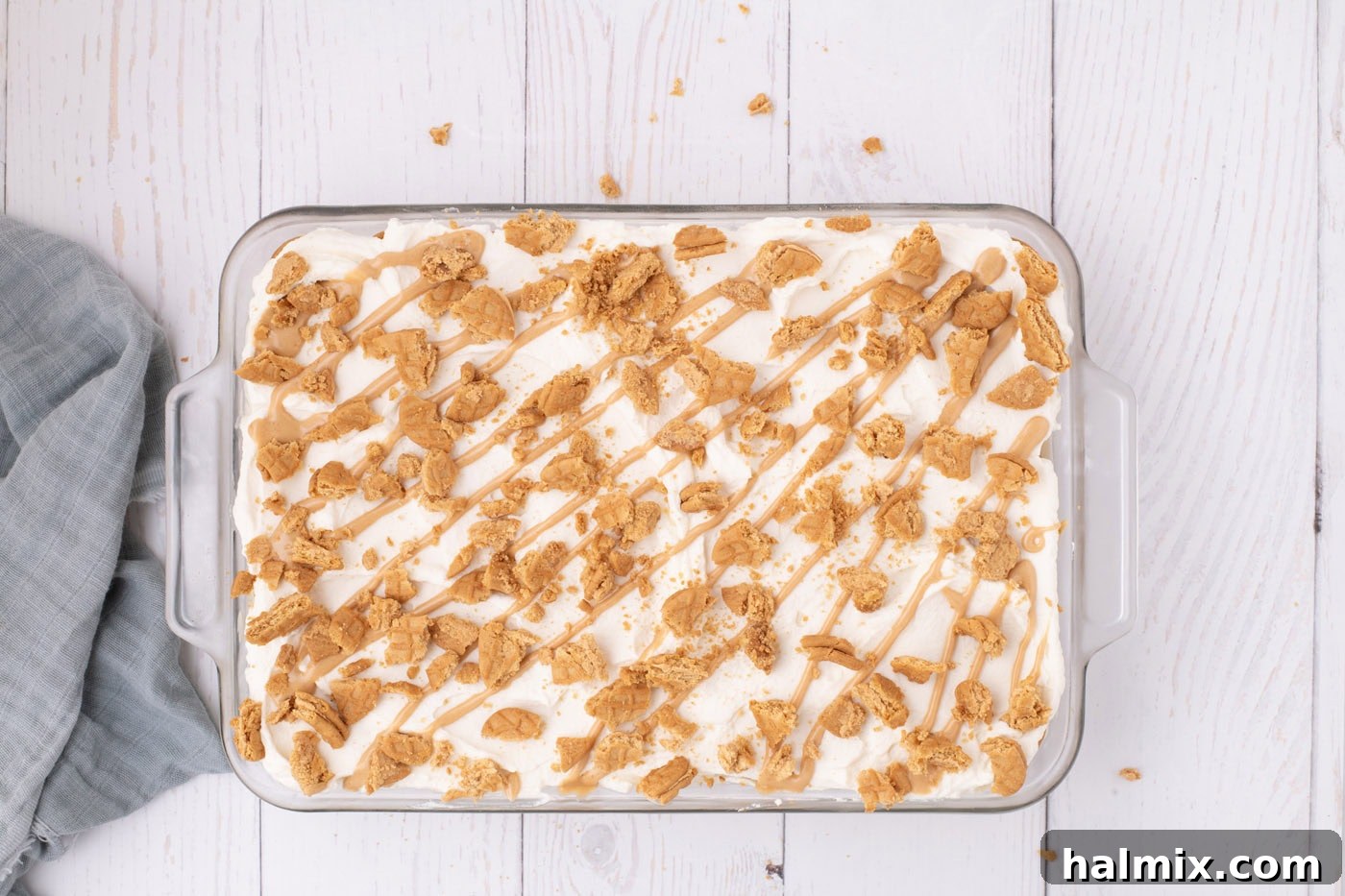 Nutter Butter Dream Cake 12 Nutter butter icebox cake in a dish with crushed cookies and peanut butter drizzle on top