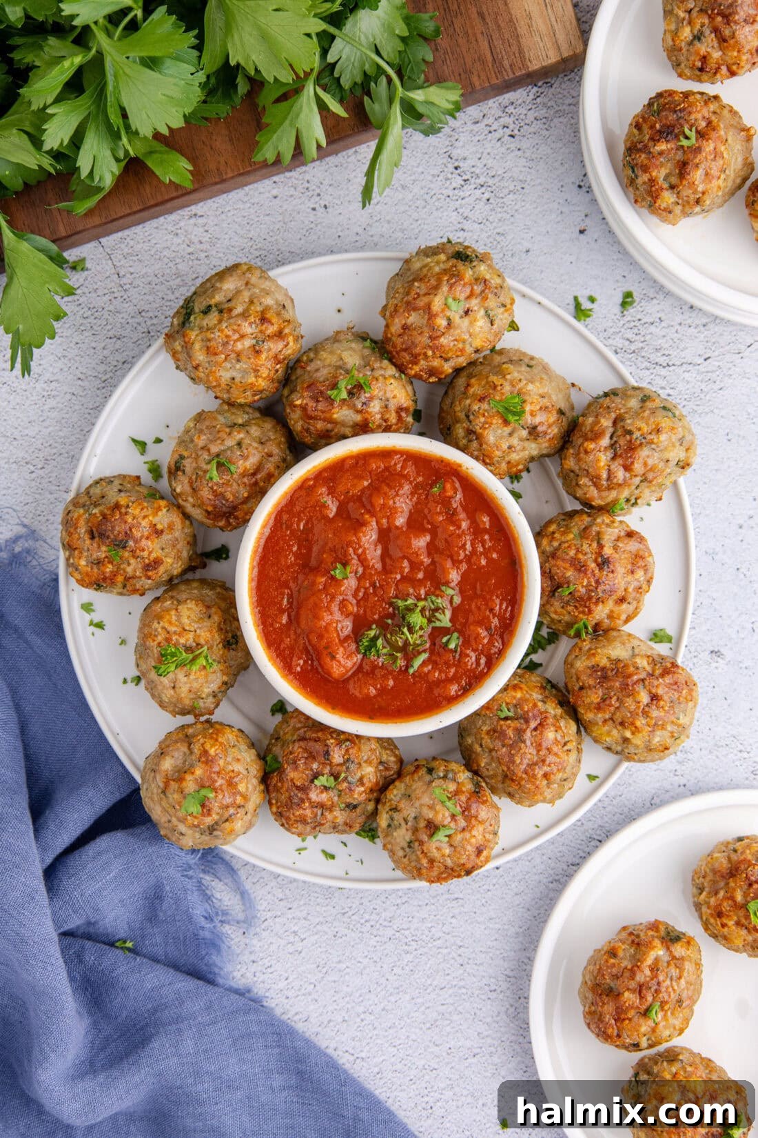 Plate of Golden Brown Baked Chicken Meatballs with a small bowl of vibrant marinara sauce for dipping.