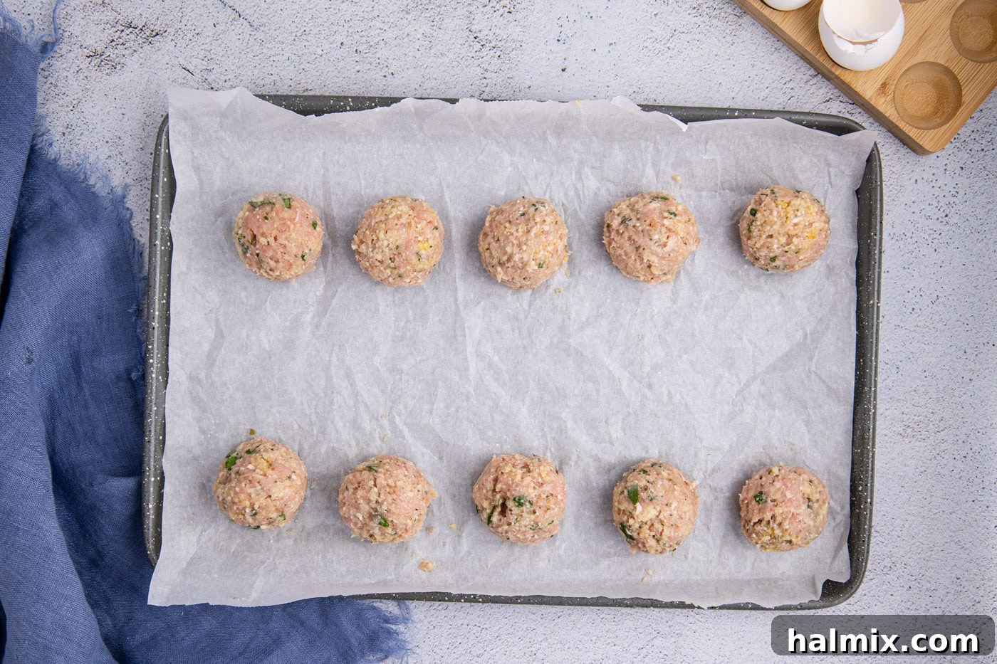 Uncooked chicken meatballs neatly arranged on a parchment-lined baking sheet, ready for chilling or baking.