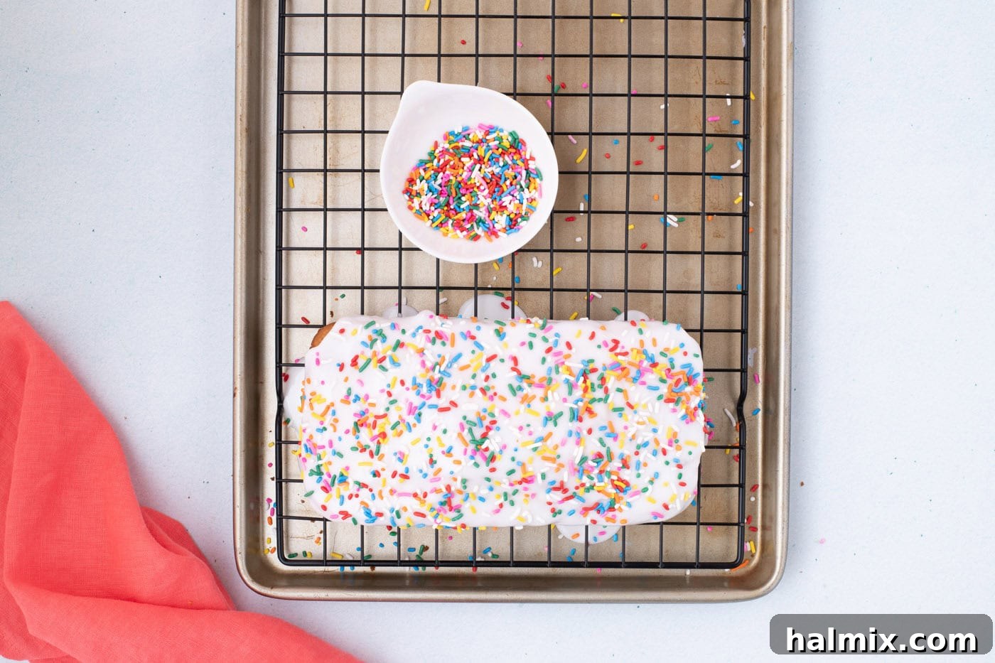 ice cream bread with glaze and sprinkles on a wire cooling rack