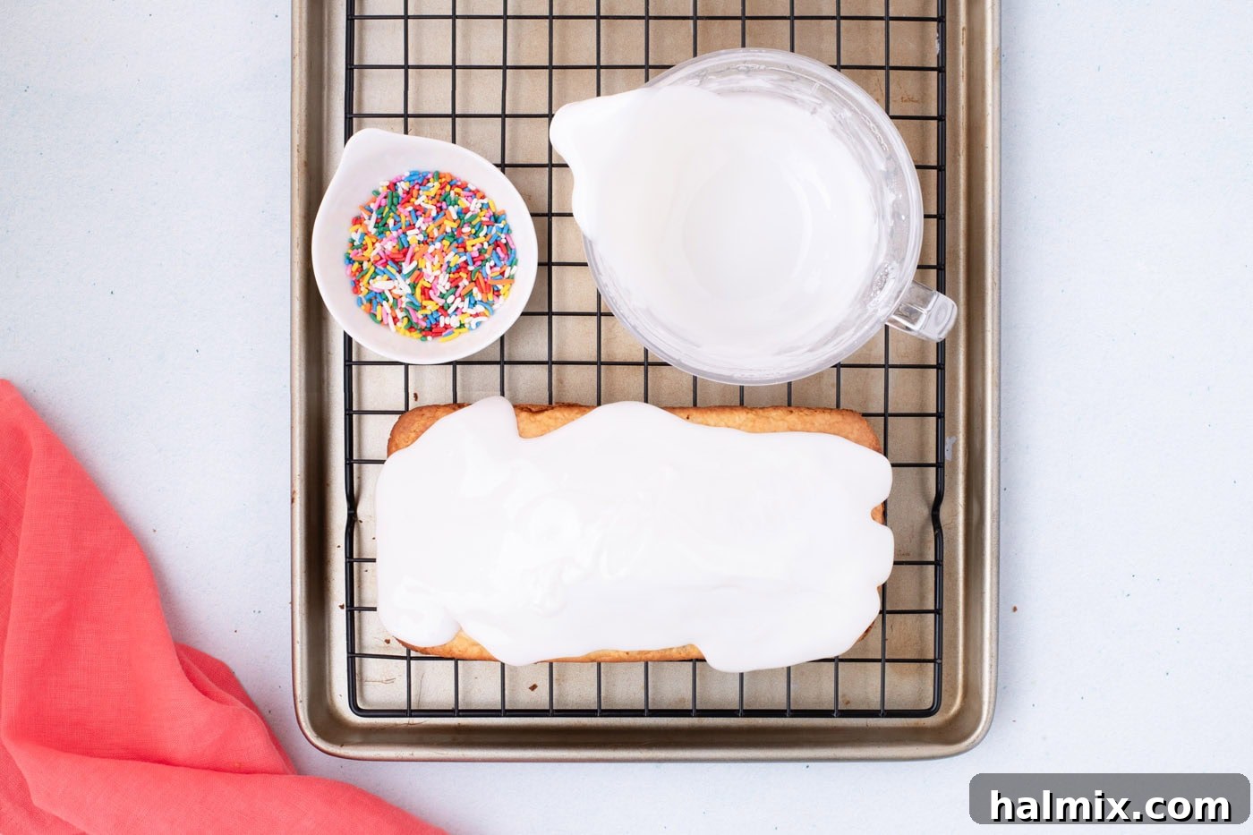vanilla glaze poured over quick bread with a bowl of sprinkles on the side