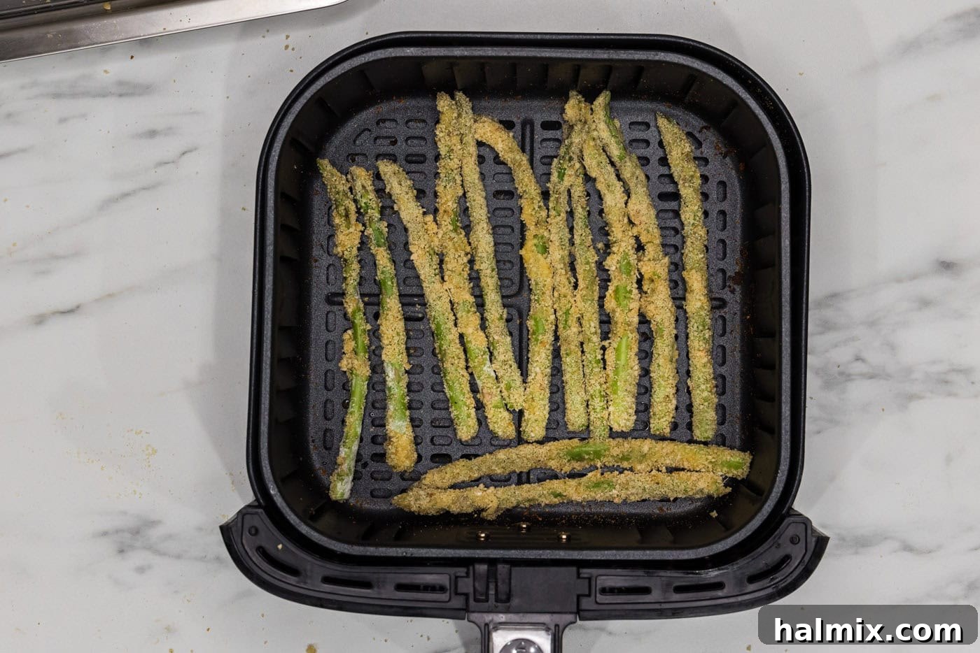 Crispy Air Fryer Asparagus 7 breaded asparagus fries in an air fryer basket