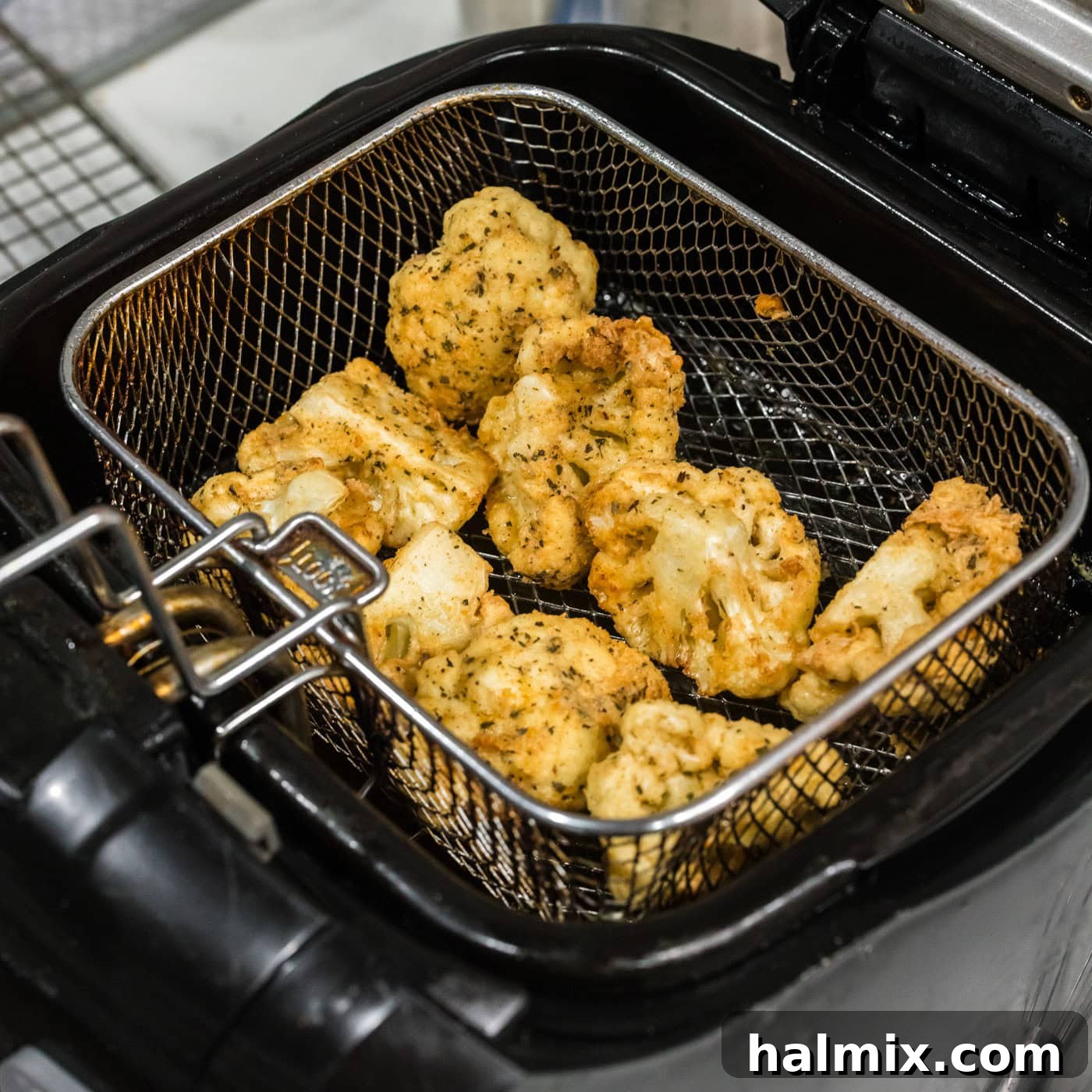 Crispy Golden Cauliflower 11 Deep-fried cauliflower florets, golden brown and crispy, draining in a fryer basket