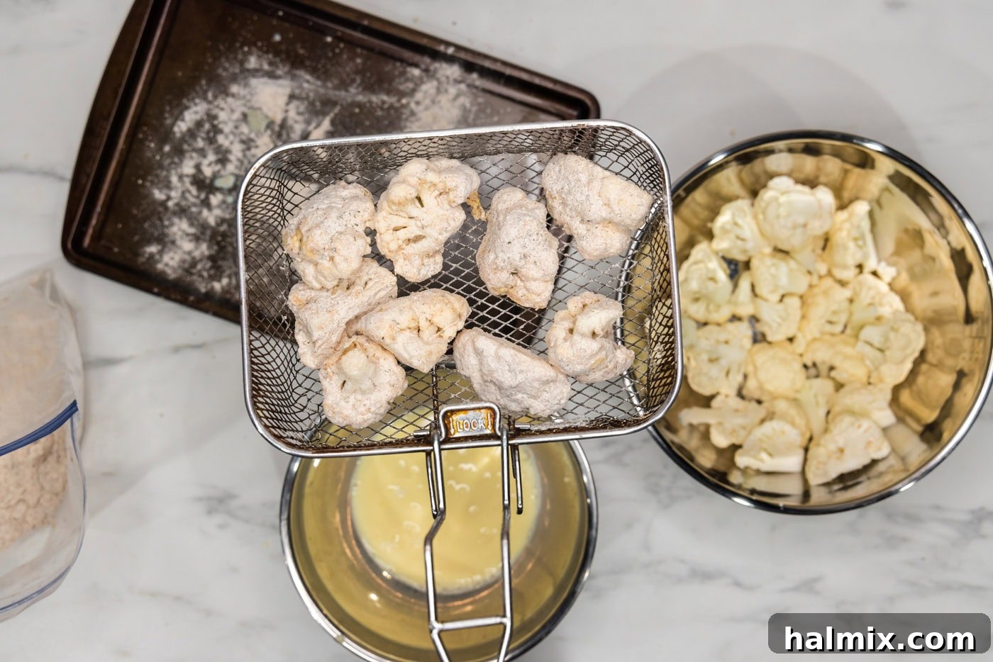 Crispy Golden Cauliflower 10 Breaded cauliflower florets carefully arranged in a deep fryer basket, ready for frying