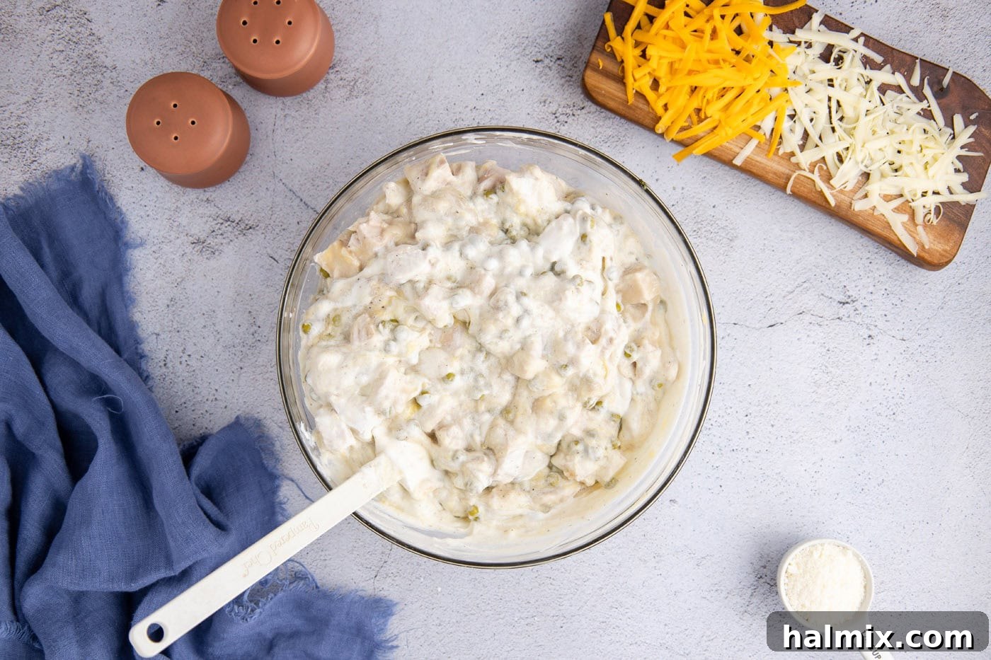 Turkey tetrazzini sauce mixture in a mixing bowl with a rubber spatula, showing its thick, creamy consistency after mixing.