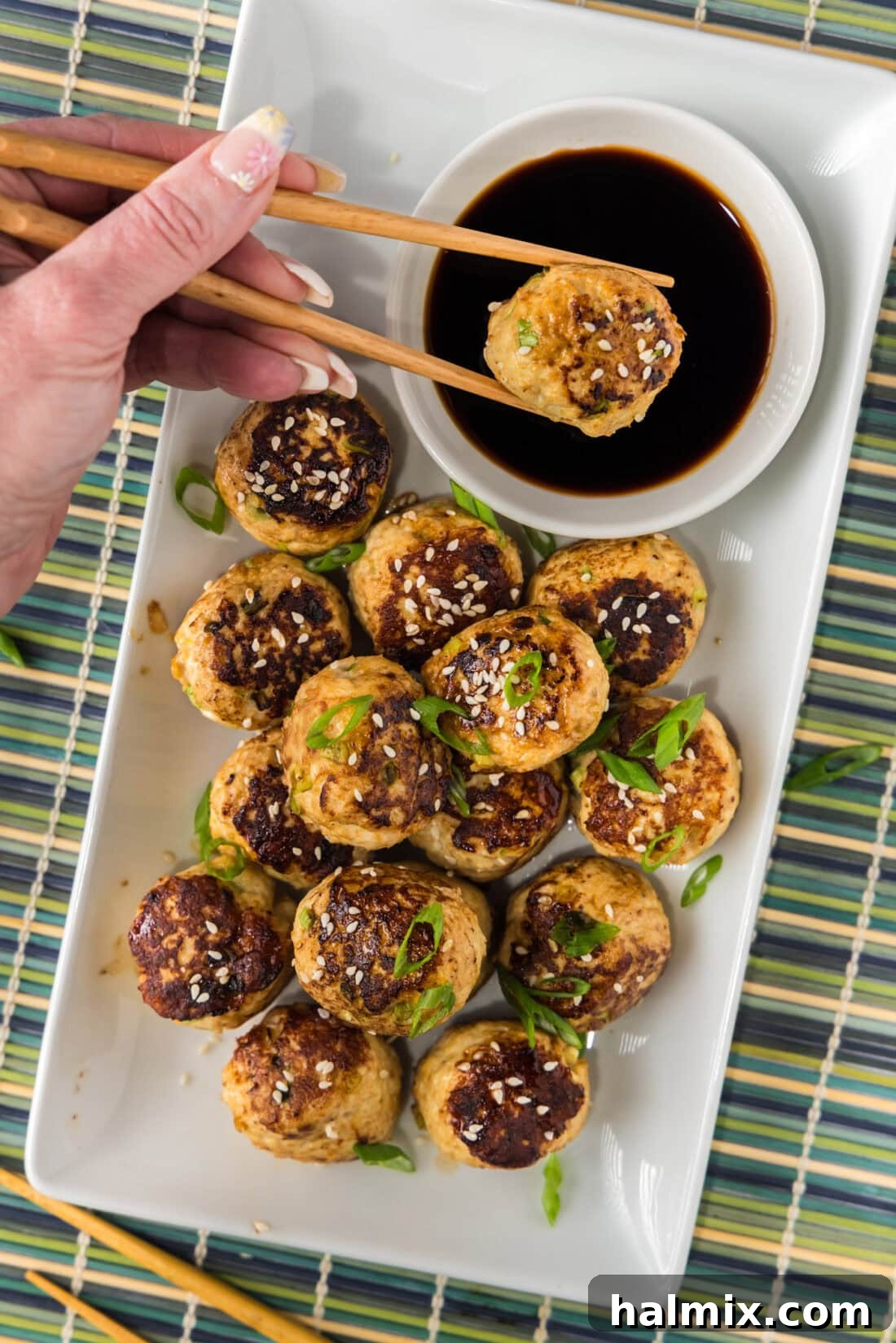 Asian Meatball being dipped into a bowl of soy sauce 