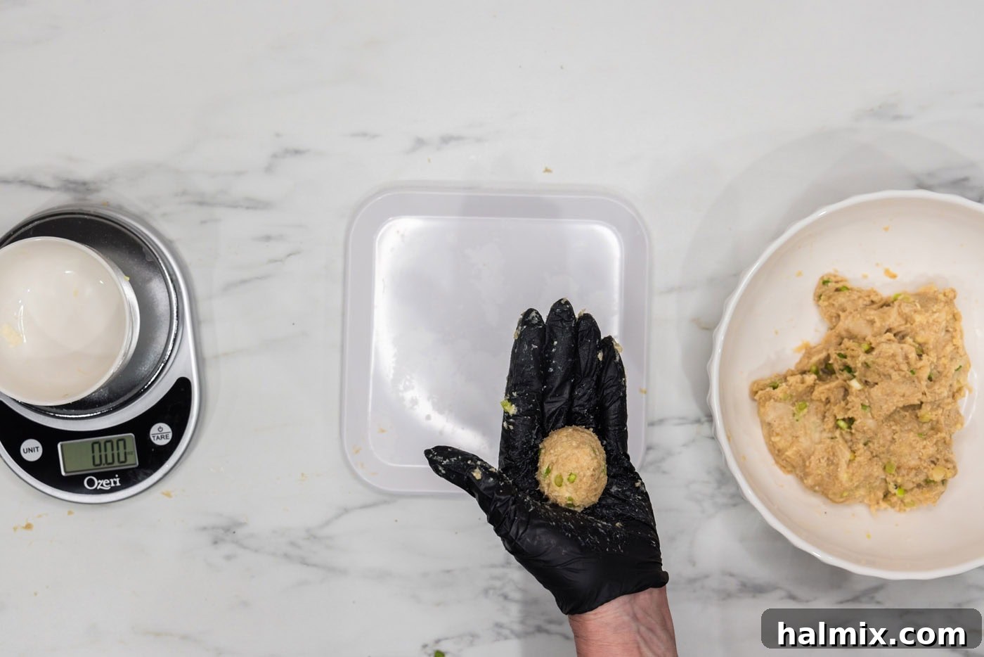 gloved hand holding chicken meatball