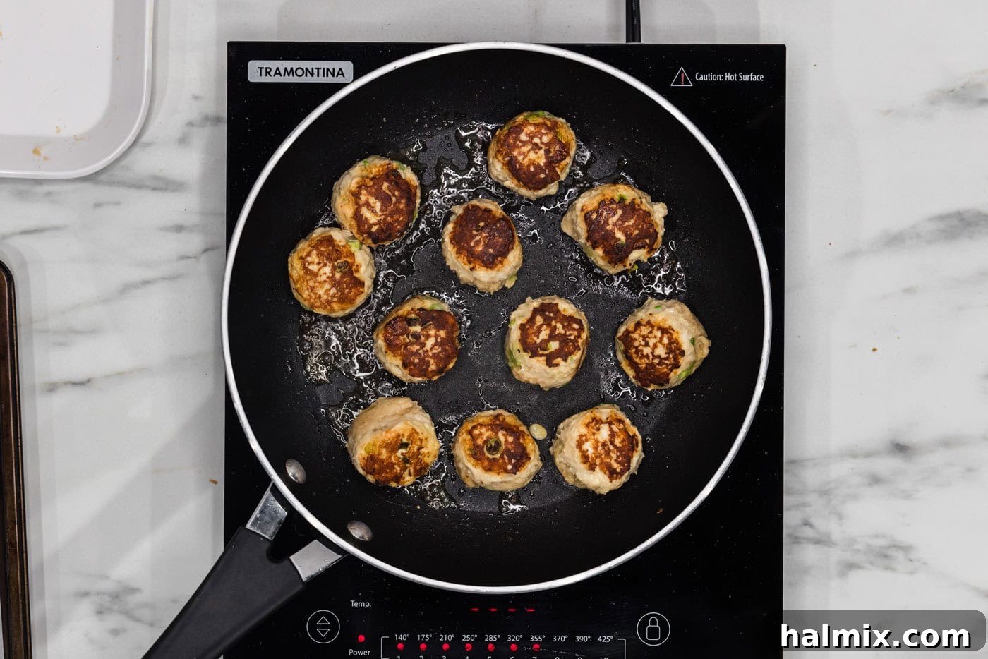 pan searing chicken meatballs in a skillet