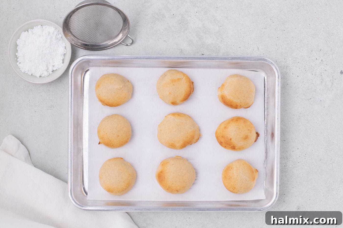 Air Fryer Oreo Magic 8 Freshly air-fried Oreos on a parchment lined baking sheet, ready for powdered sugar