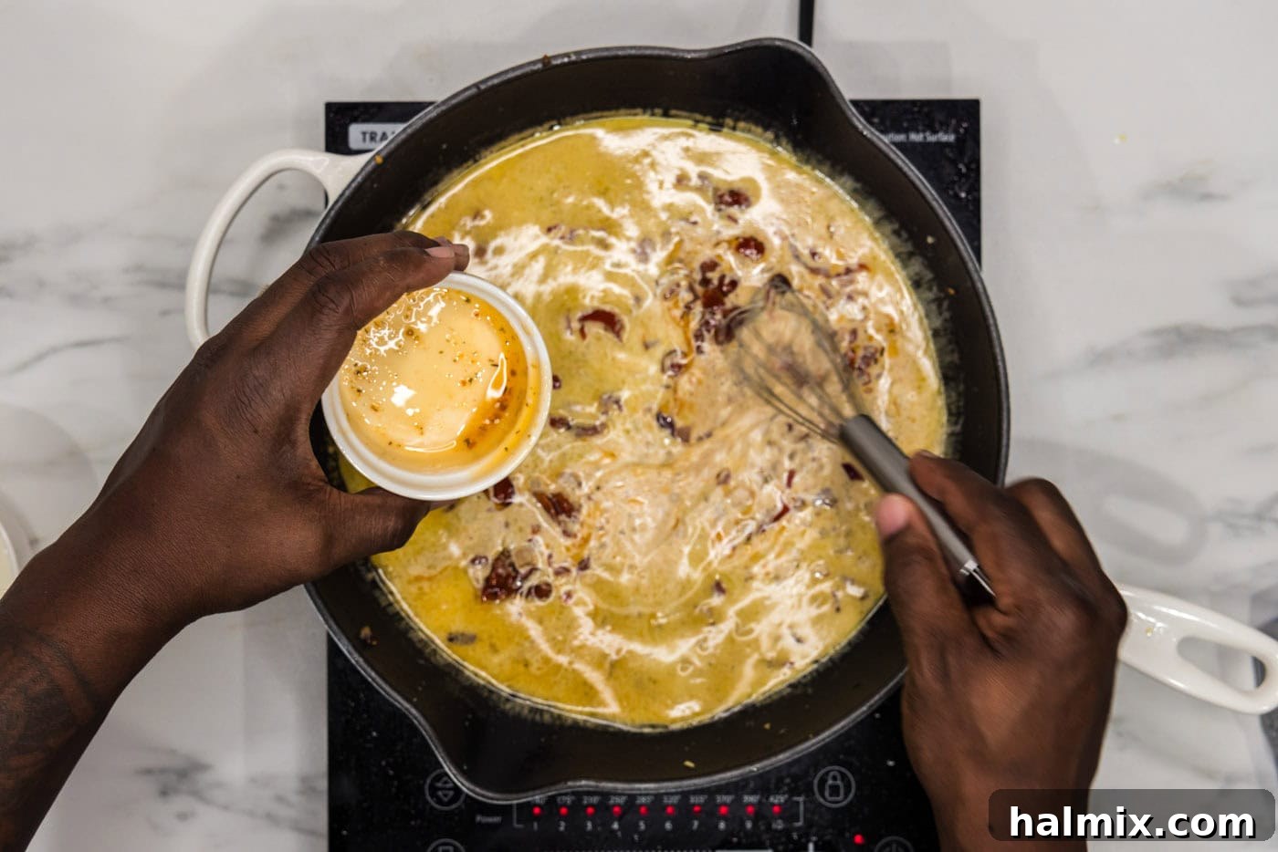 whisking chicken base into skillet with red onion, garlic, and heavy cream