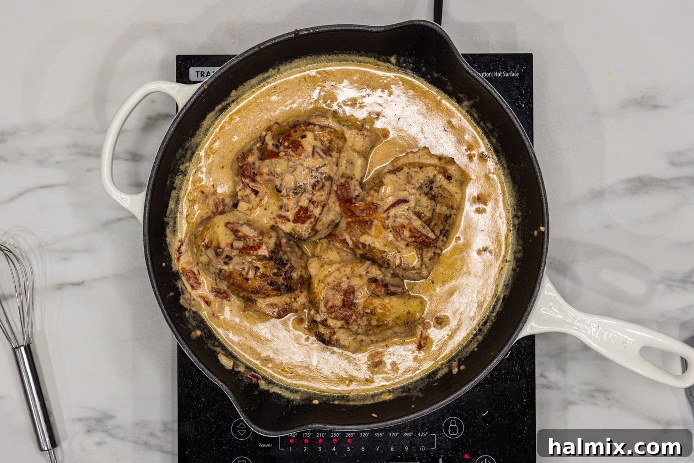 chicken thighs in a skillet with sun dried tomatoes and cream sauce
