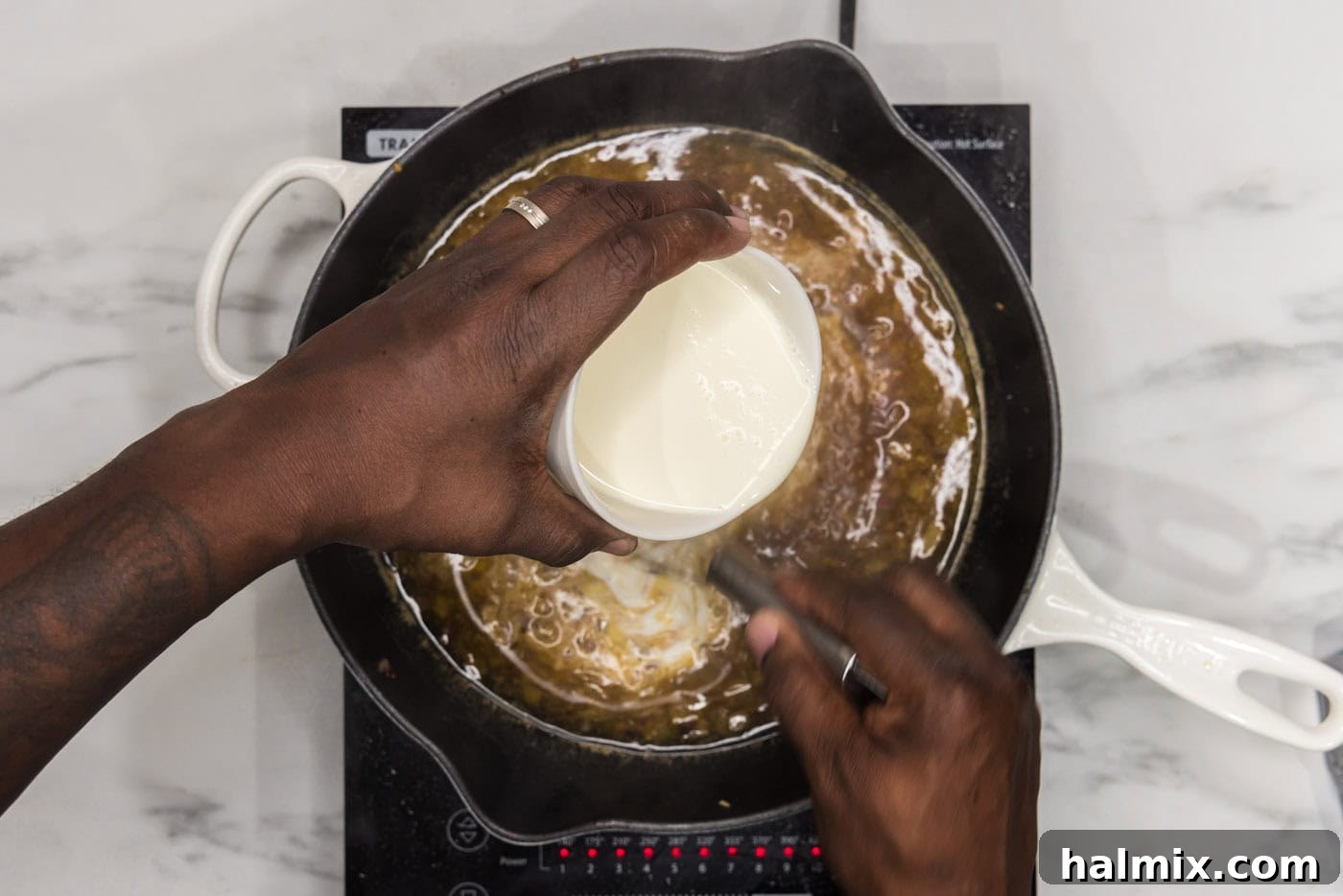 whisking heavy cream into skillet with onions and garlic