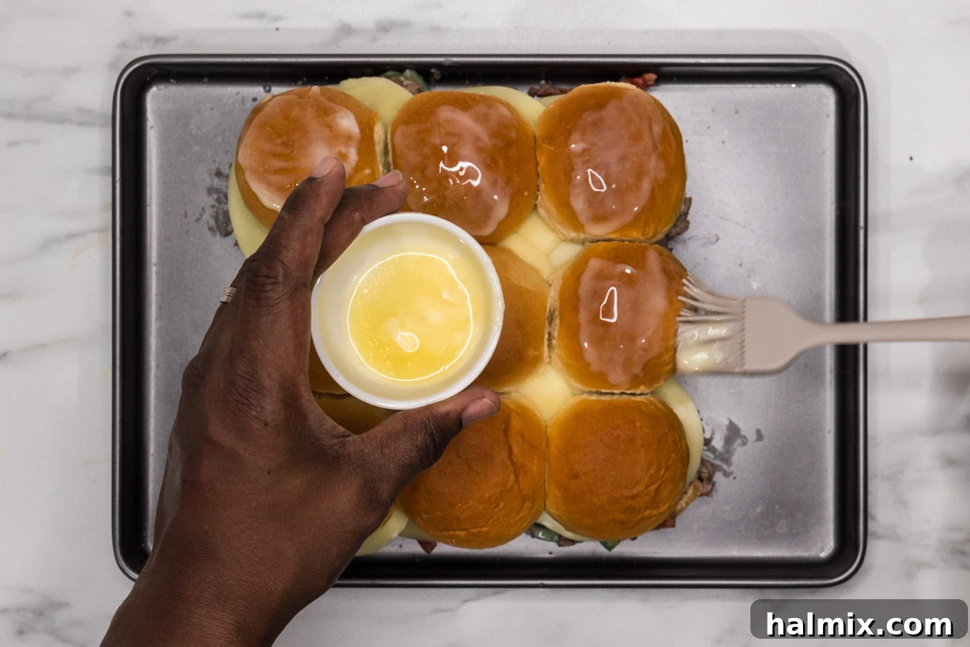 basting philly cheesesteak sliders with melted butter