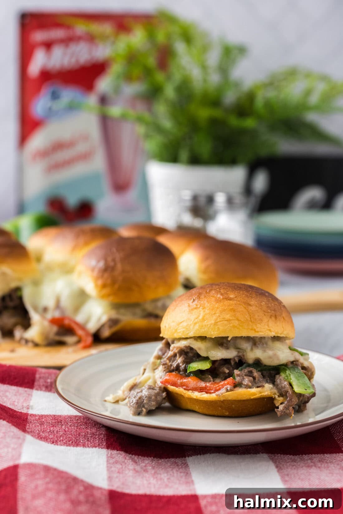 Philly Cheesesteak Slider Delights 13 Philly Cheesesteak Slider on a plate with more Philly Cheesesteak Sliders in the background