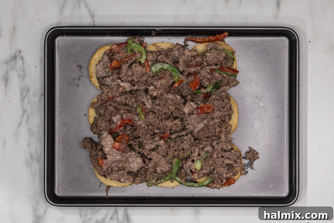 shaved beef and bell pepper mixture on top of slider buns