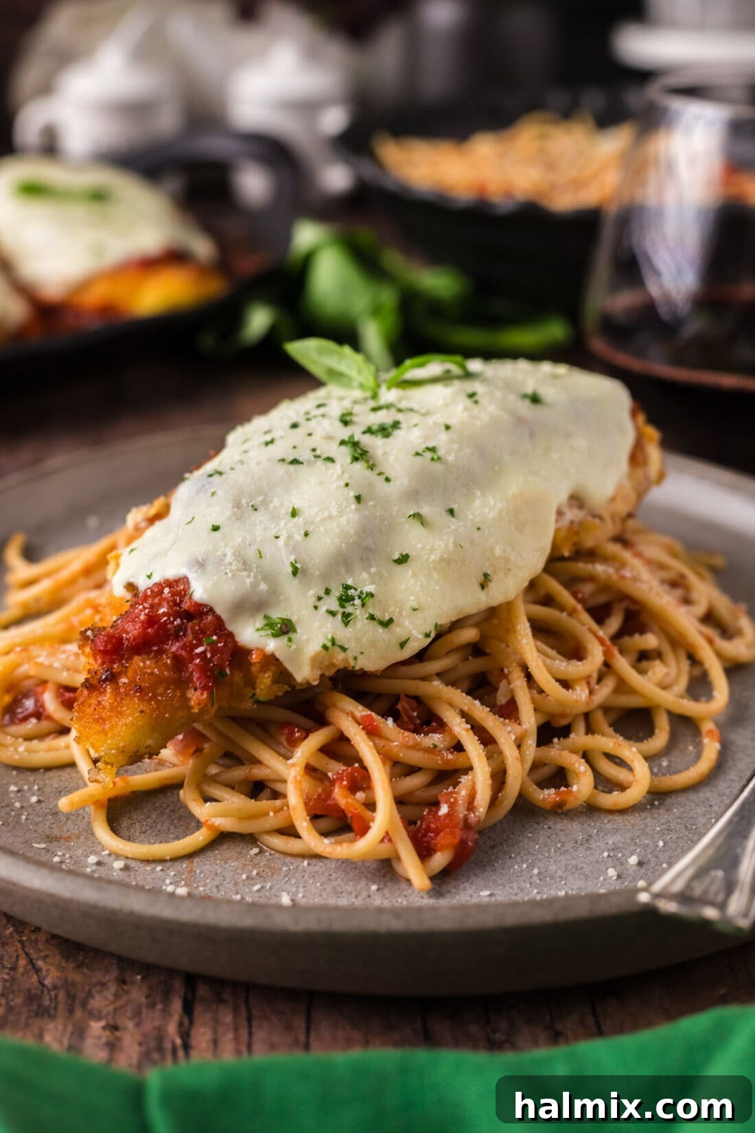 Classic Chicken Parmesan served over spaghetti on a white plate, garnished with fresh parsley.
