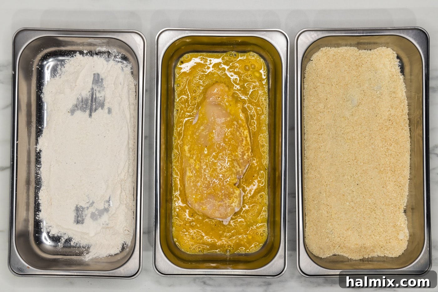 Chicken cutlet being dipped in egg mixture.