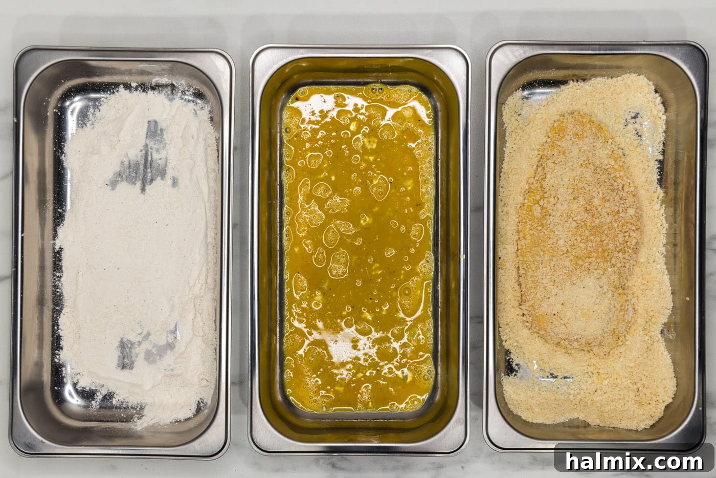 Chicken cutlet being pressed into panko breadcrumbs.