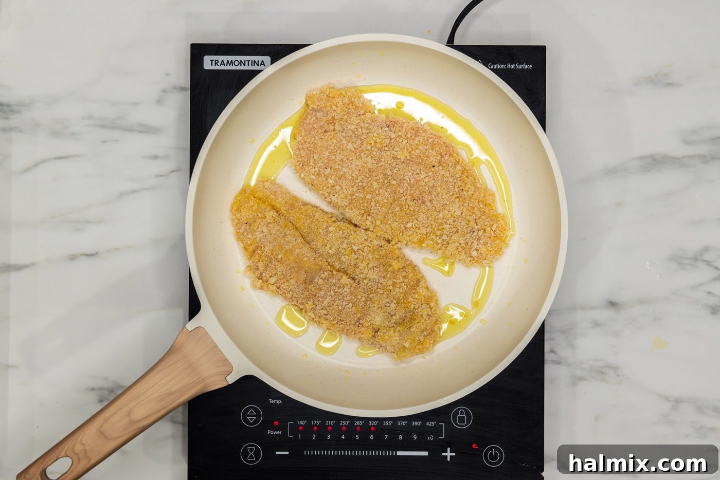 Pan-frying a dredged chicken cutlet in a skillet until golden brown.
