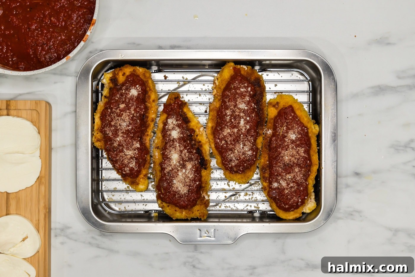 Marinara sauce spread on top of a fried chicken cutlet, ready for cheese.