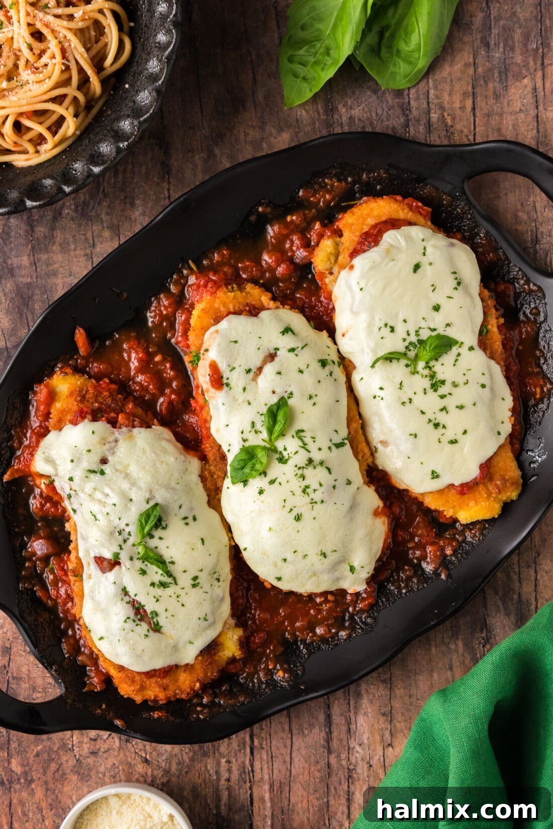 A large platter displaying multiple servings of golden brown Chicken Parmesan with melted cheese and rich marinara.