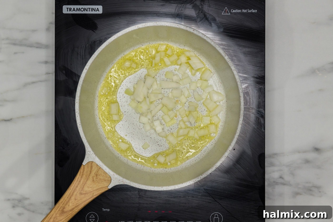 Minced onion sautéing in olive oil in a skillet.