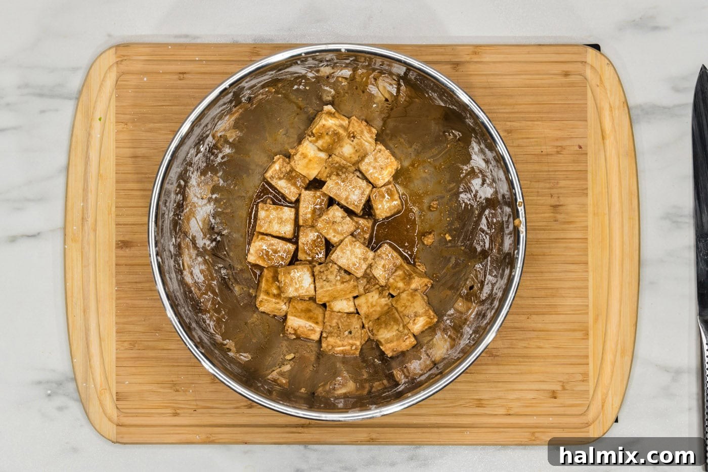 Unbelievably Crispy Air Fryer Tofu 8 cubed tofu in a bowl with soy sauce, cornstarch, and sesame oil