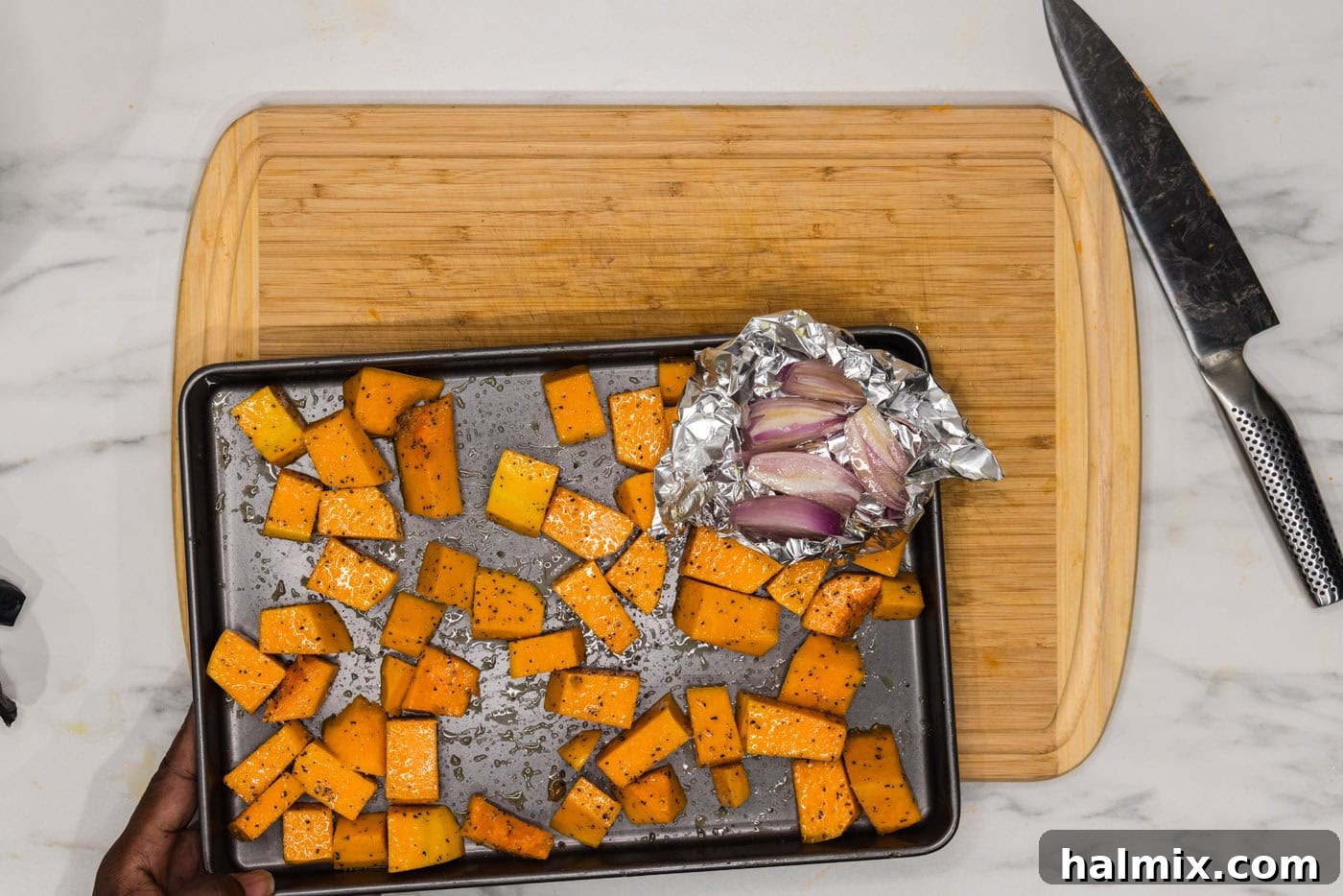 Velvety Butternut Squash Pasta 8 butternut squash cubes on a baking sheet with shallots in a foil packet