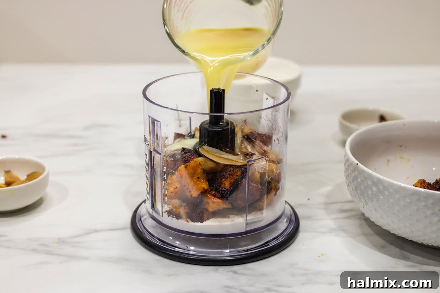 Velvety Butternut Squash Pasta 10 pouring chicken broth into mini food chopper with squash and shallots