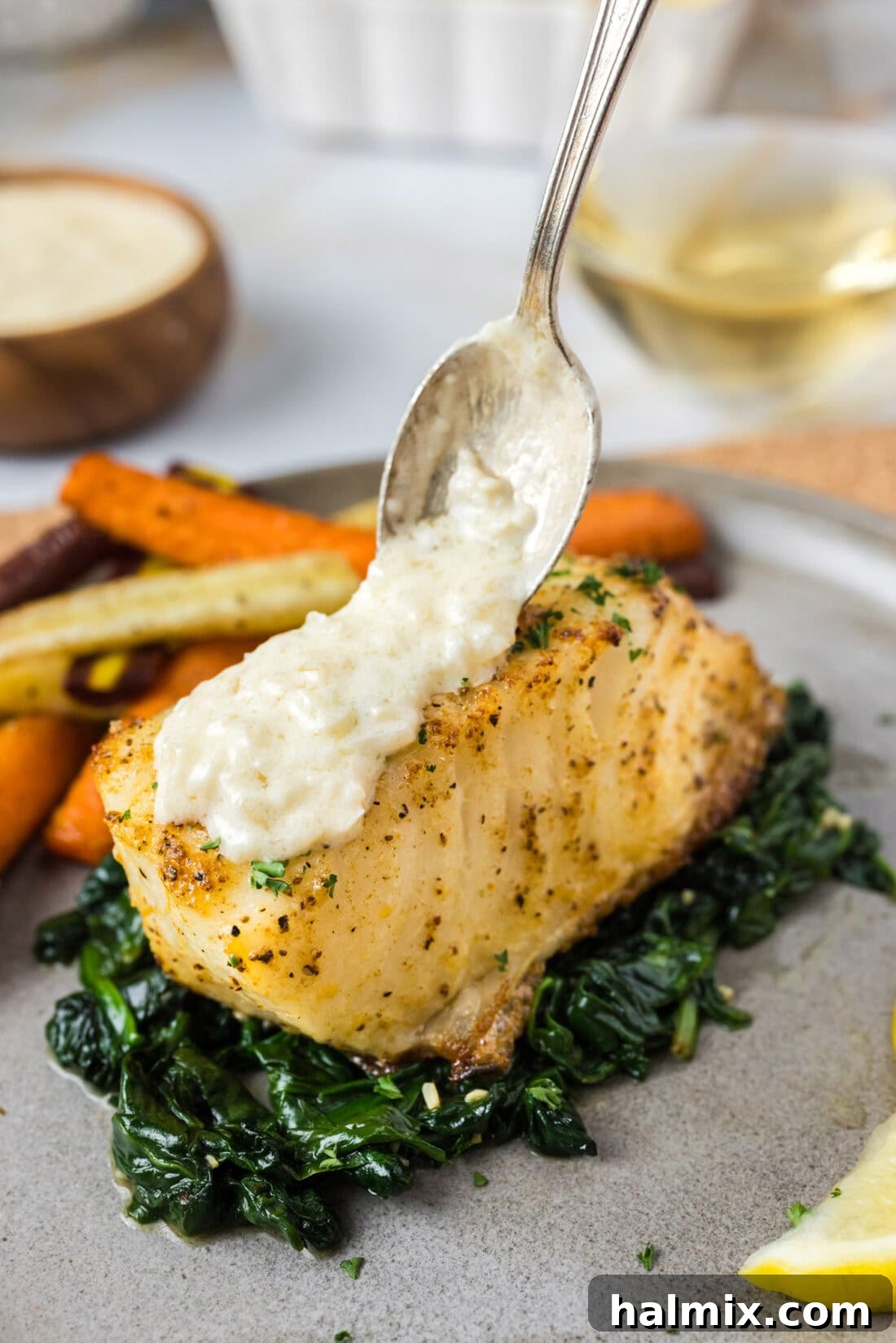 Beurre Blanc Sauce being spooned over perfectly baked Chilean Sea Bass fillets