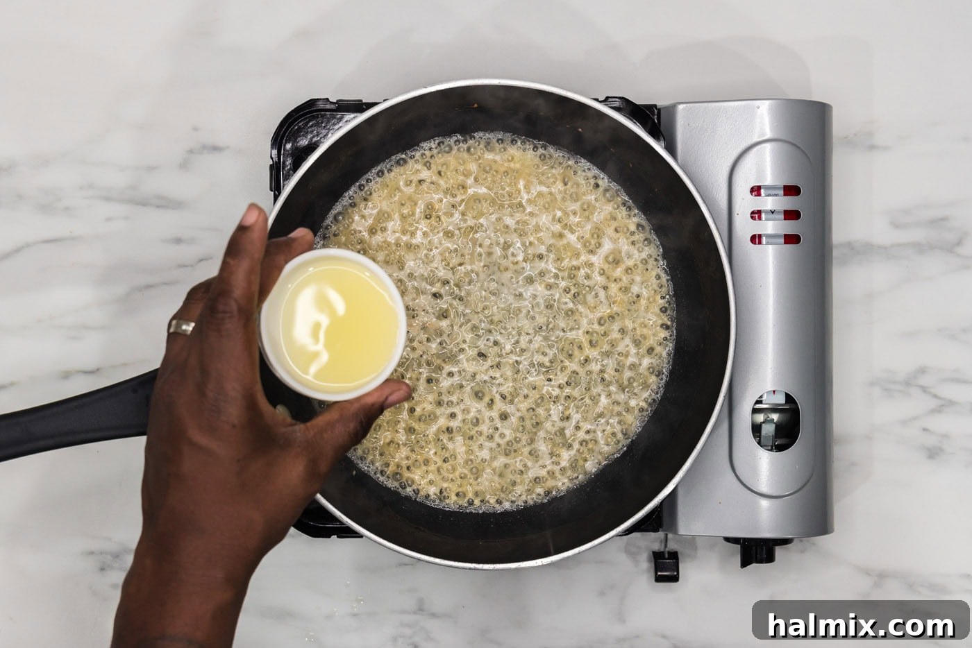 pouring lemon juice into skillet with white wine, shallots, and garlic