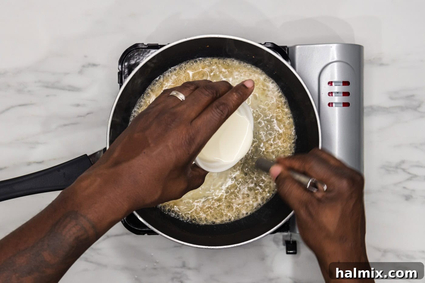whisking heavy whipping cream into the simmering sauce in a skillet