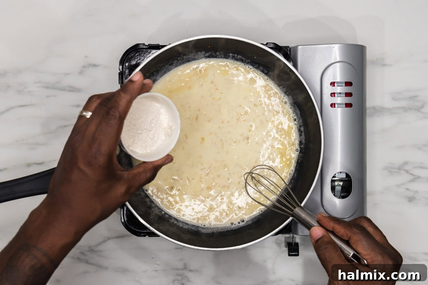 whisking flour into the sauce in a skillet to thicken it