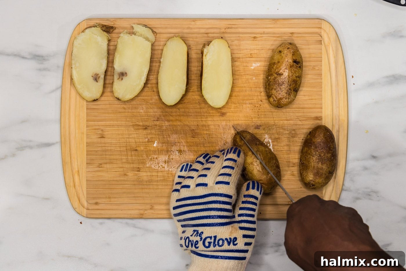 Loaded Potato Skins 7 slicing potato in half lengthwise on a cutting board