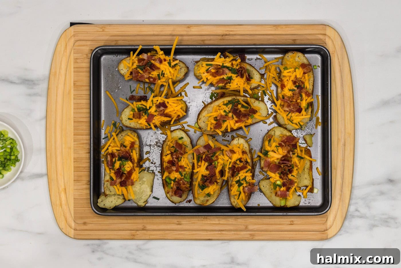 Loaded Potato Skins 10 bacon, shredded cheese, chives, and green onions on potato skins on a baking sheet