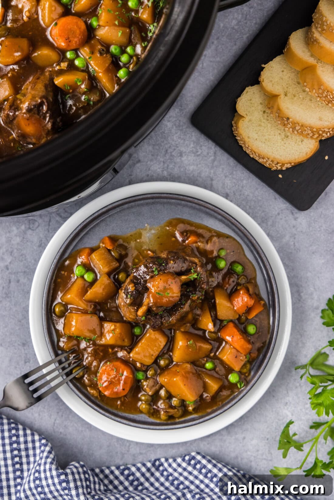 Melt-in-Your-Mouth Slow Cooker Oxtail 2 Slow Cooker Oxtail on a plate with a fork, garnished with fresh herbs.