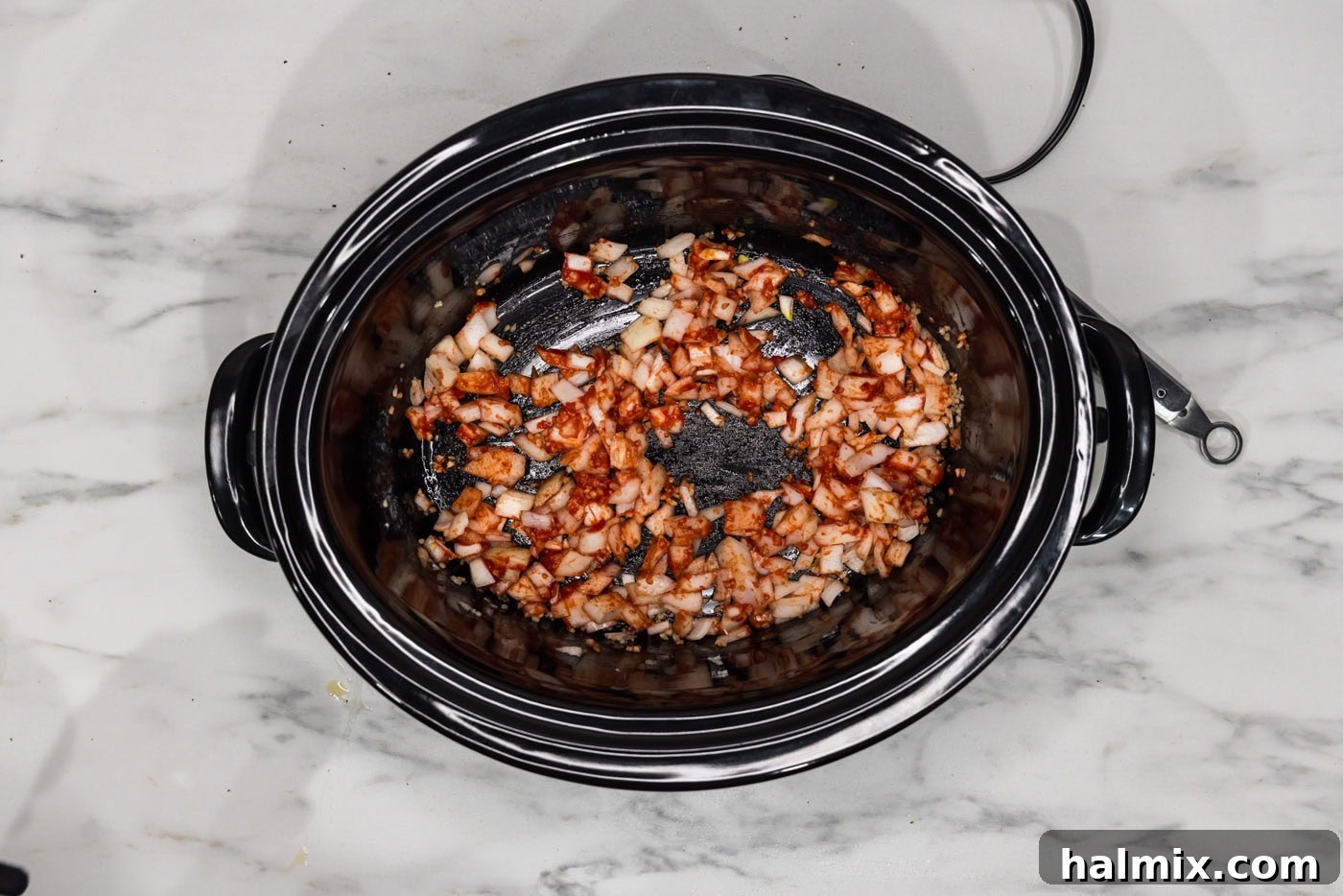 Melt-in-Your-Mouth Slow Cooker Oxtail 6 Tomato paste, chopped onion, and minced garlic simmering in a crockpot.