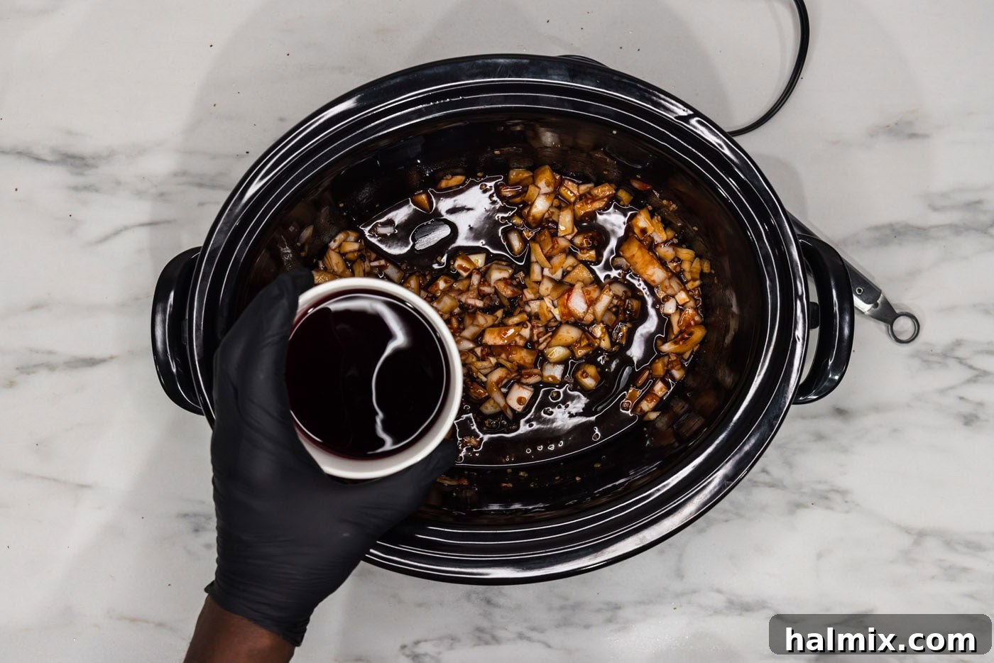 Melt-in-Your-Mouth Slow Cooker Oxtail 7 Adding red wine to the crockpot, which already contains onion, tomato paste, soy sauce, and beef base.