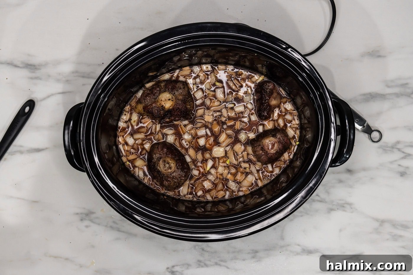 Melt-in-Your-Mouth Slow Cooker Oxtail 8 Seared oxtails added to the red wine and onion braising liquid in the crockpot.