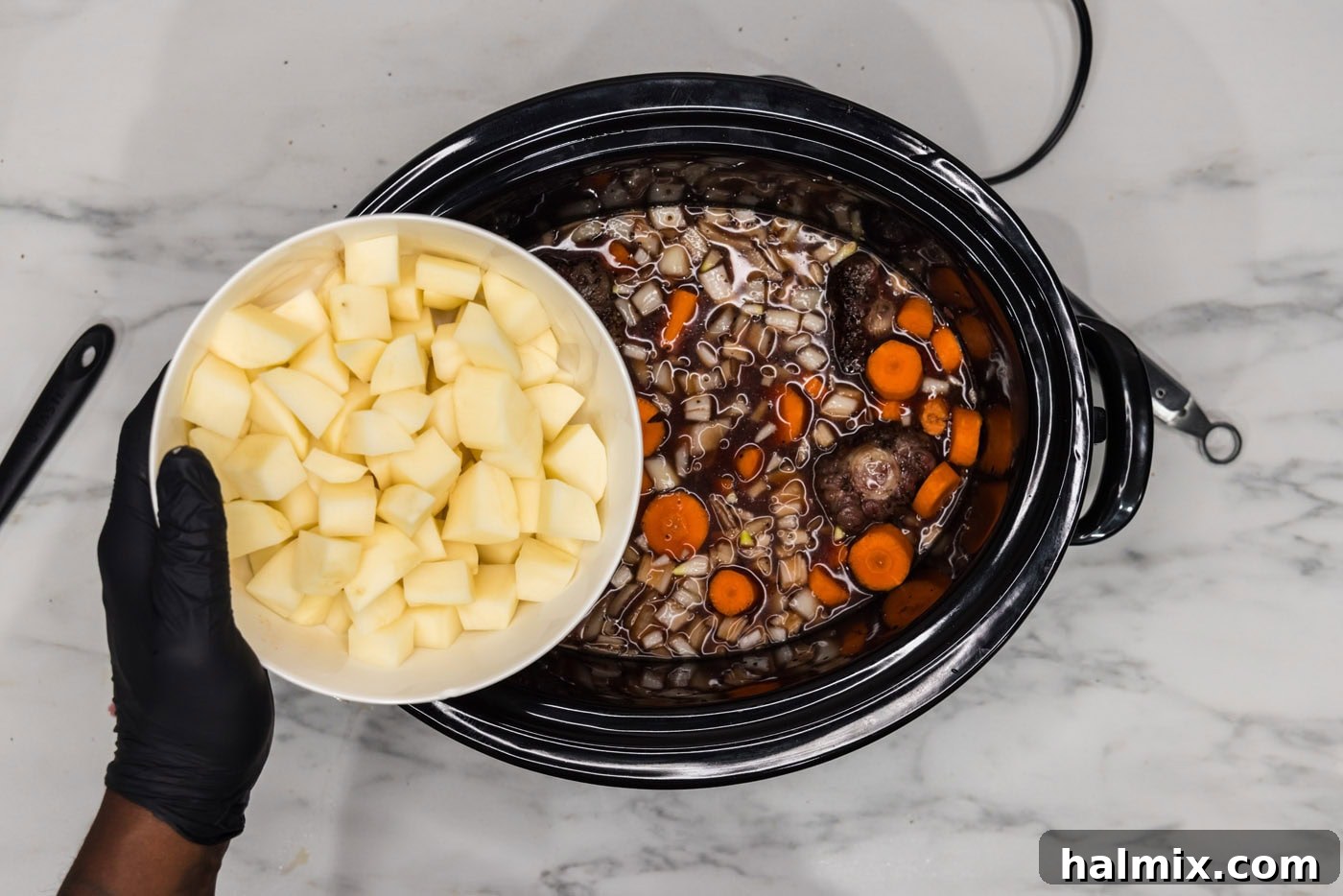 Melt-in-Your-Mouth Slow Cooker Oxtail 9 Adding potatoes and carrots to the slow cooker with the oxtail.
