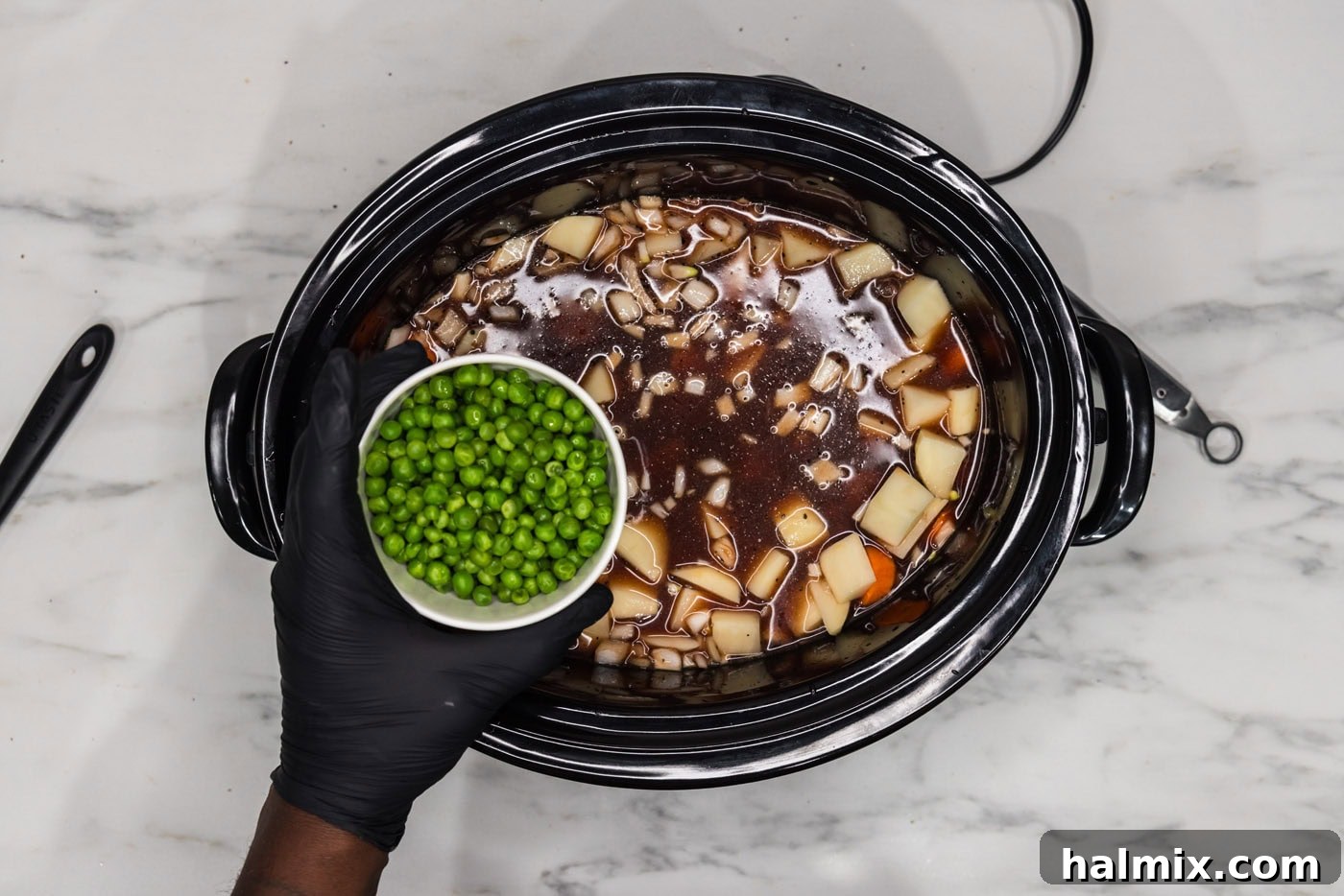 Melt-in-Your-Mouth Slow Cooker Oxtail 10 Adding half of the frozen peas to the oxtail and vegetable stew in the crockpot.