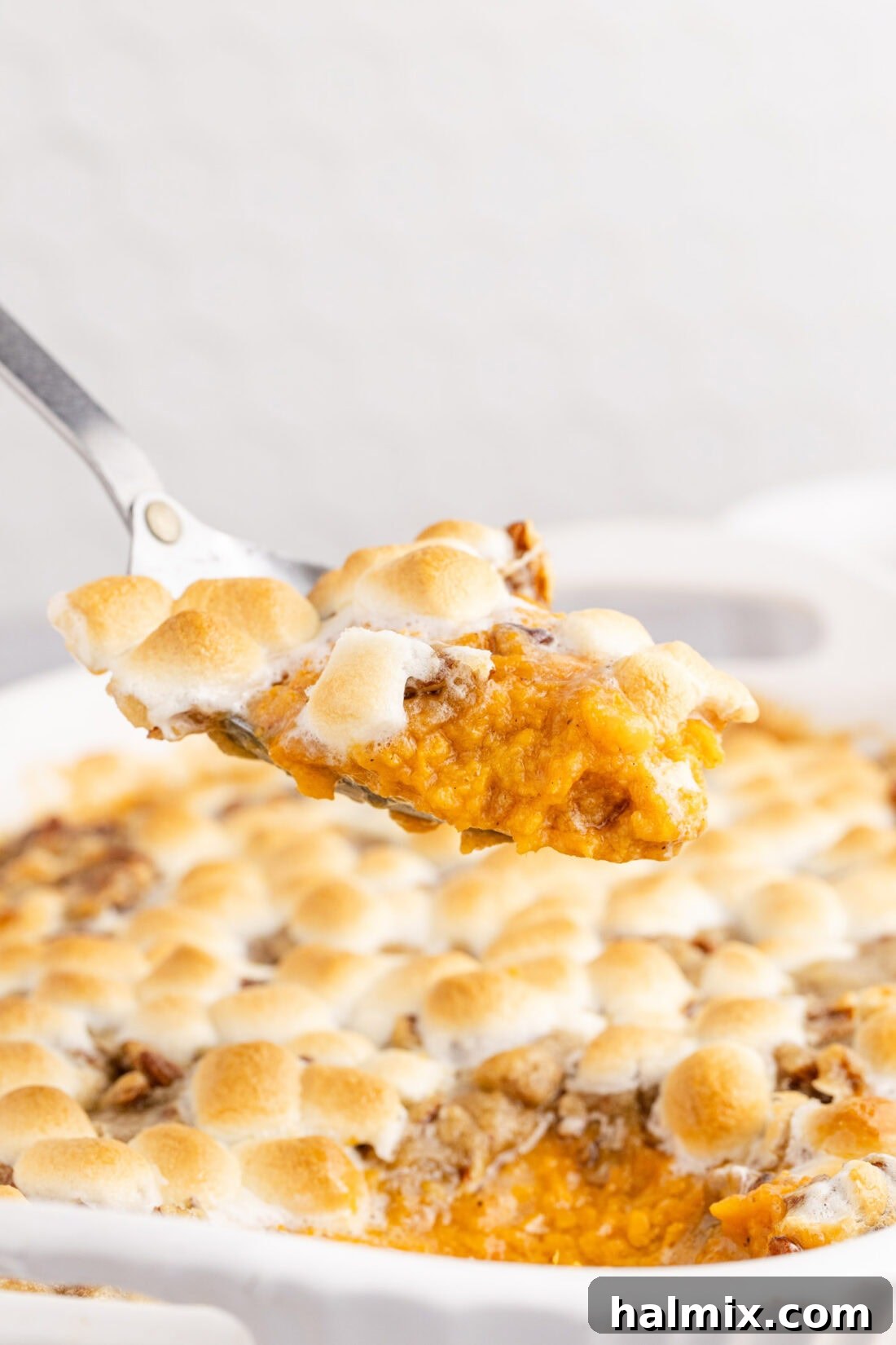 Heavenly Sweet Potato Bake 3 Spoonful of Sweet Potato Casserole held above the Sweet Potato Casserole, showing layers of mashed potato, streusel, and marshmallows