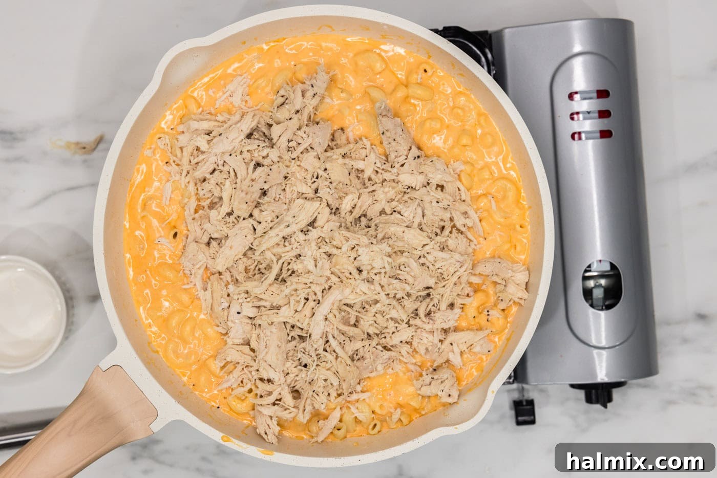 shredded chicken added to skillet of buffalo mac and cheese