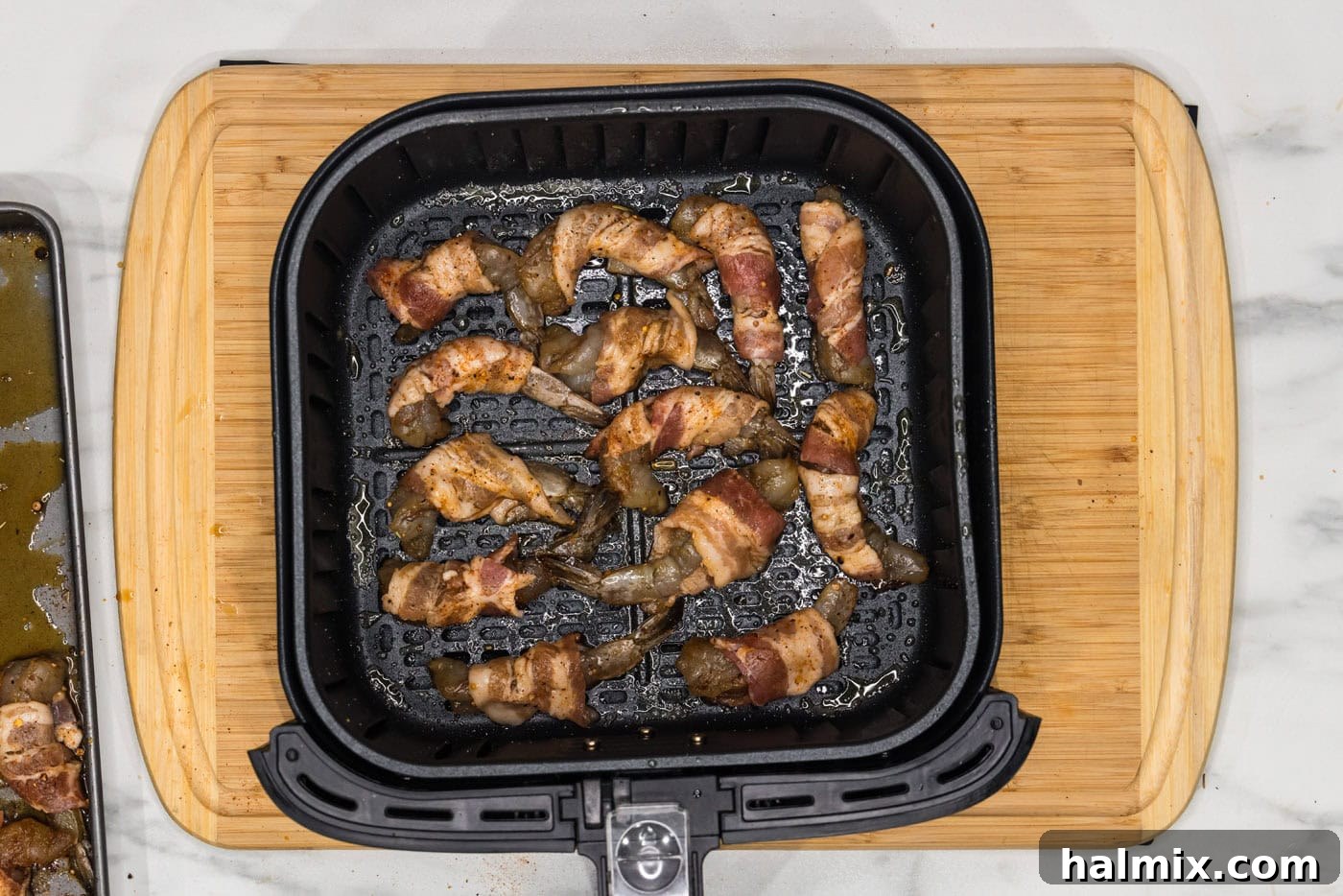 bacon wrapped shrimp in an air fryer basket, perfectly arranged for cooking
