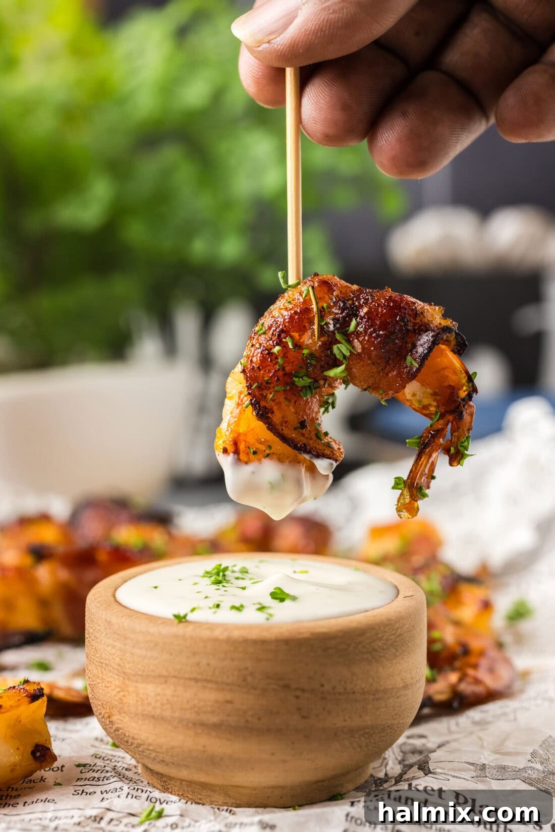 Air Fryer Bacon Wrapped Shrimp on a toothpick dipped in ranch sauce, showing crispy texture