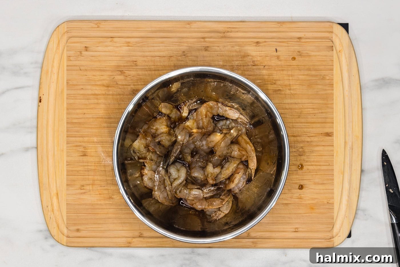 shrimp in a bowl with soy sauce and maple syrup glaze, being tossed to coat