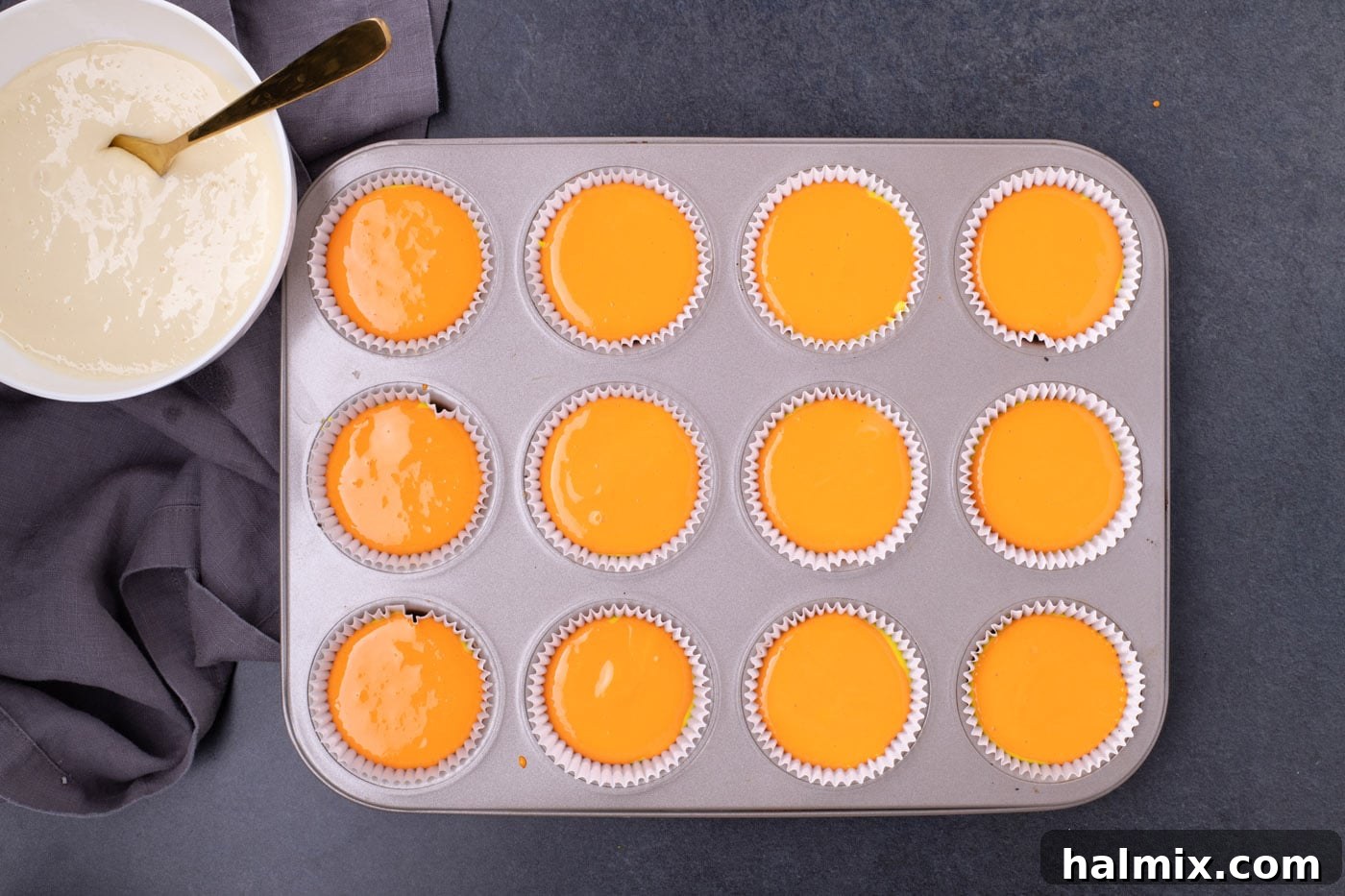 Spooky Sweet Candy Corn Cheesecake Minis 9 Orange cheesecake batter layered on top of the yellow layer in a cupcake pan.